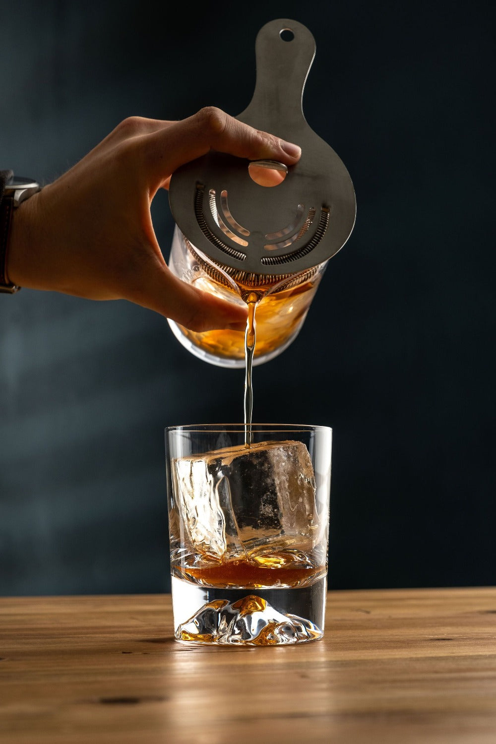 Old Fashioned Cocktail being strained from honeycomb mixing glass into mountain rocks glass. photo by Jordan Hughes of High Proof Preacher