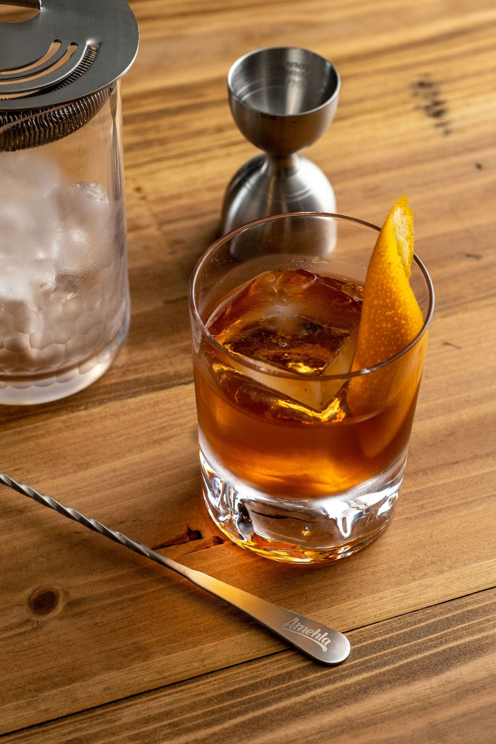 Old Fashioned in an Amehla Co. Mountain Rocks Old Fashioned Glass surrounded by honeycomb mixing glass, strainer, jigger, and barspoon. Photo by Jordan Hughes of High Proof Preacher.